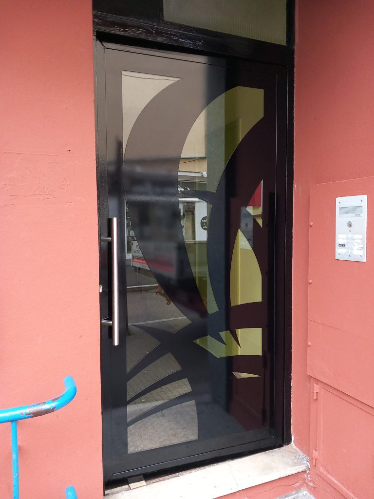Fabrication d une porte d'immeuble avec décor et verre.